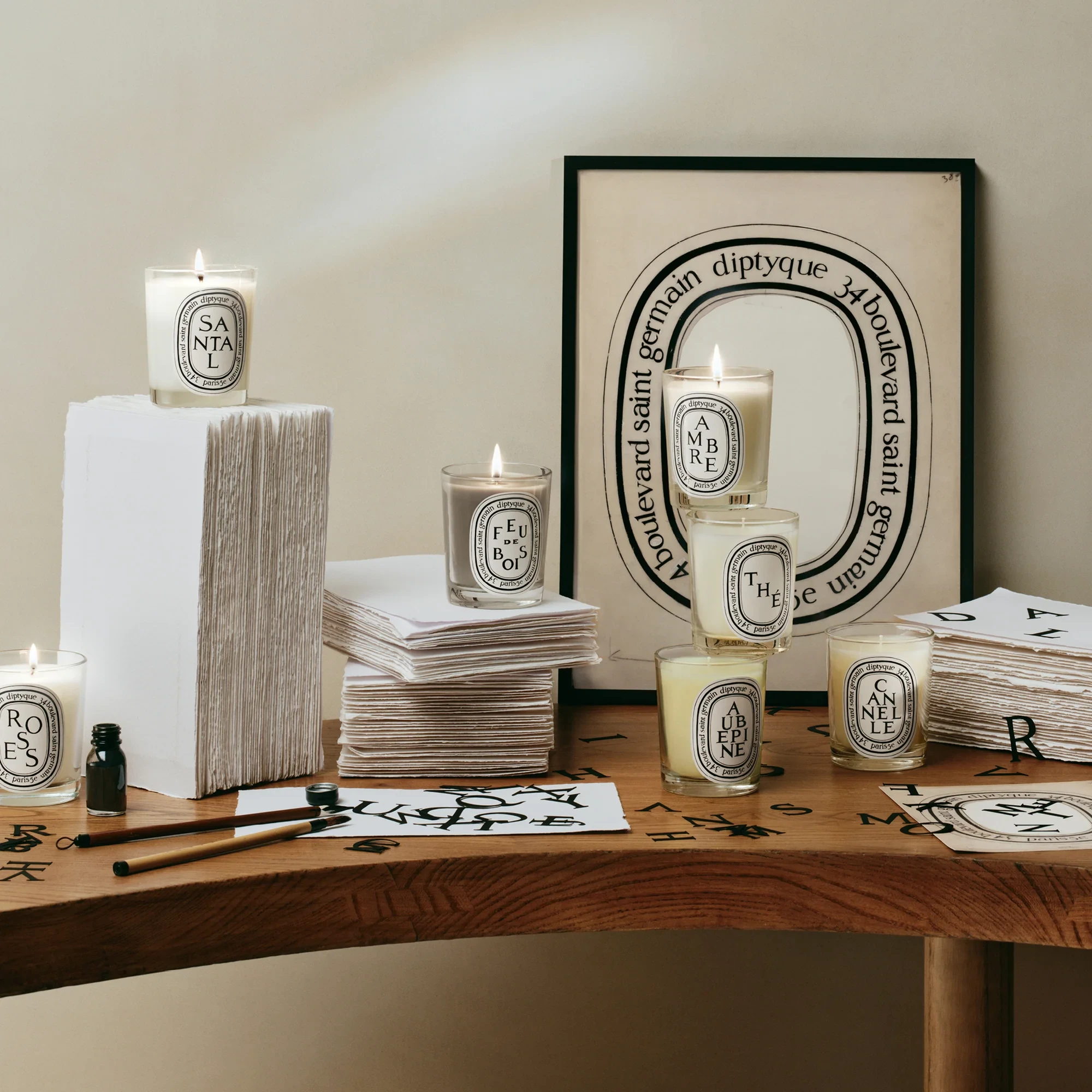 Diptyque candles arranged with framed artwork and handmade paper